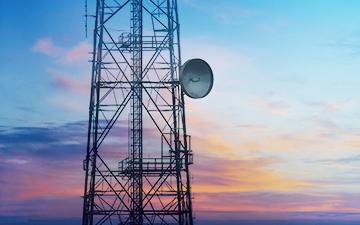 Celluar and satellite internet tower in front of a colorful sunset